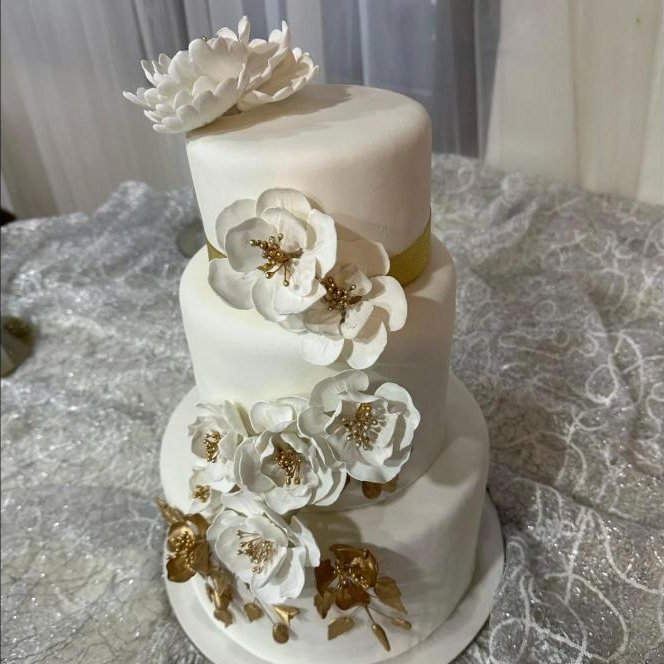 Pastel de bodas de tres pisos con flores blancas y doradas