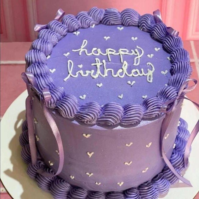 Pastel morado con mensaje Happy Birthday y moños